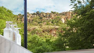 A bathroom with a view of rocky cliffs and greenery.