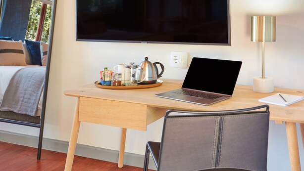 A modern room with a wooden desk, a laptop, a coffee pot, and a tray of breakfast items. - The Cliffside Boutique Getaway (Randburg)