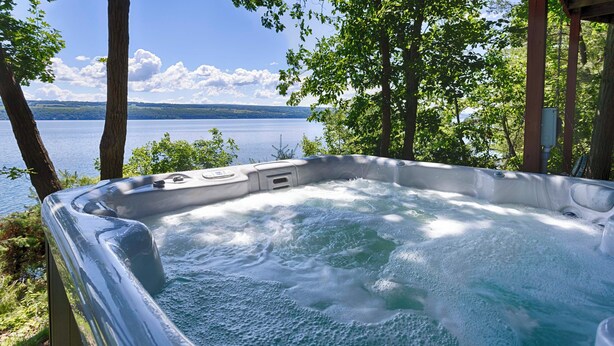 A hot tub with a view of a lake and mountains.