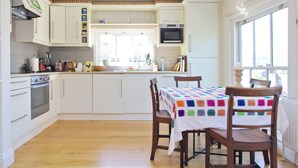 A kitchen with white cabinets, a microwave, and a table with a colorful tablecloth.