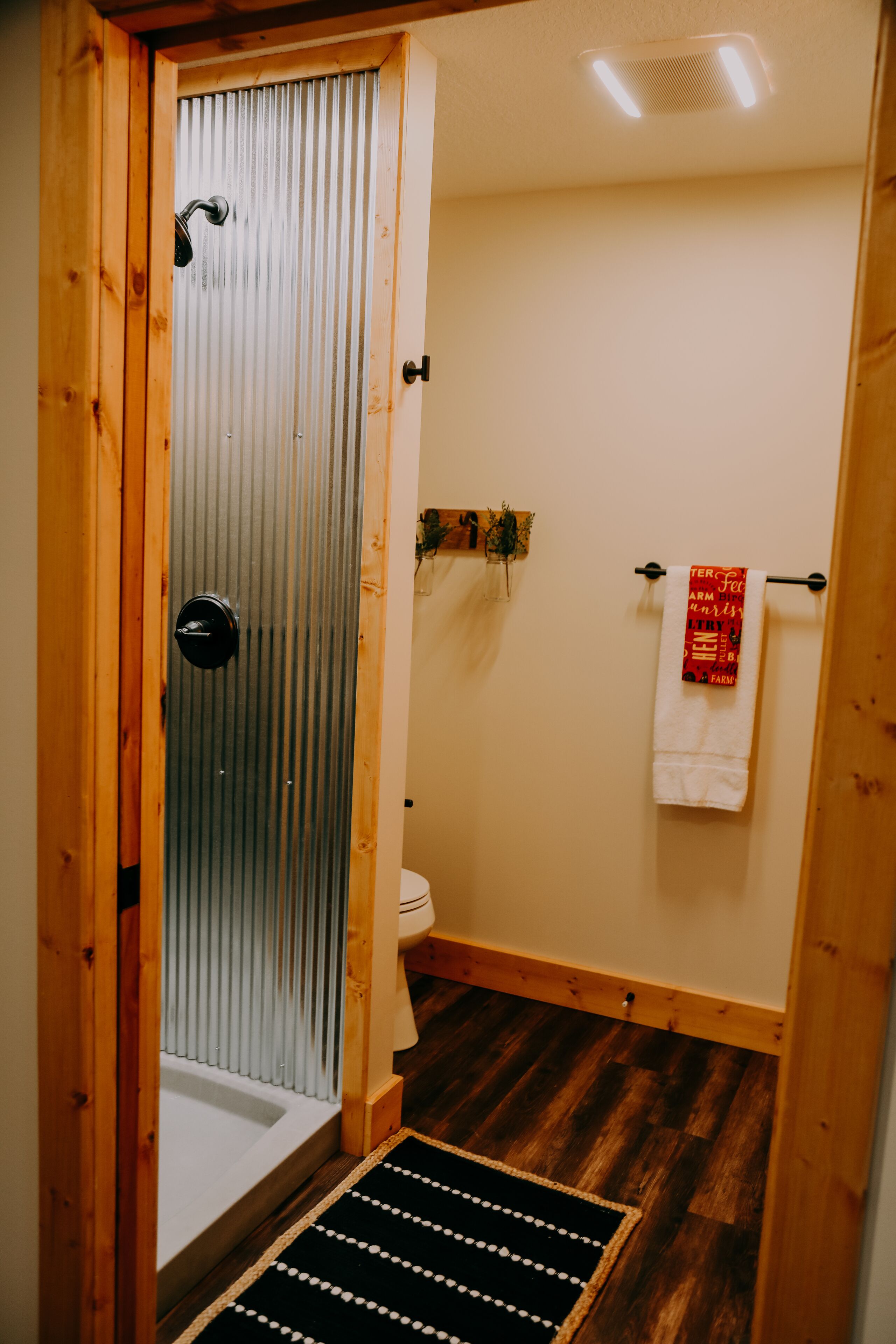 A bathroom with a shower, toilet, and a towel rack with a towel.