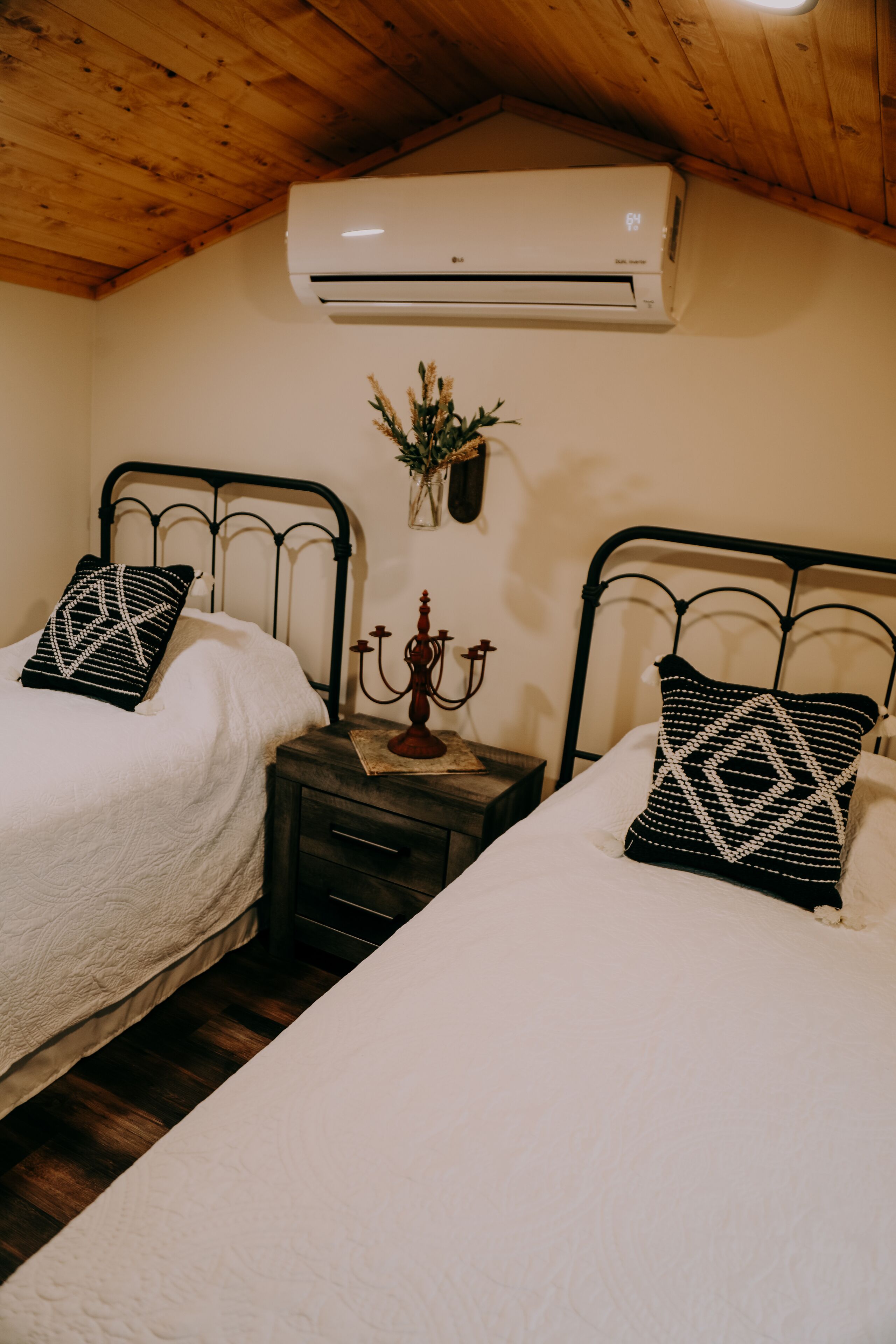 Ein Schlafzimmer mit zwei Betten, einem Nachttisch, einem Kandelaber und einer Klimaanlage.