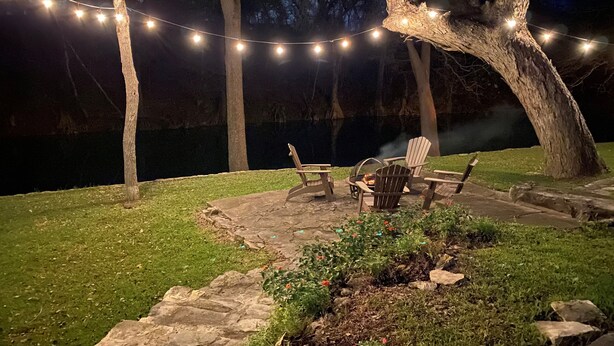A patio area with stone steps, a fire pit, and Adirondack chairs.