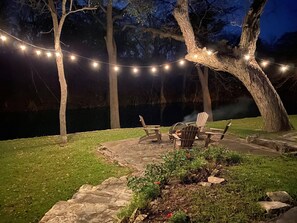 A patio area with stone steps, a fire pit, and Adirondack chairs.