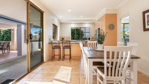 A modern kitchen with a dining area, featuring a sliding glass door leading to an outdoor patio. - Beachside living takes a smart & stylish turn with this well appointed apartment (Lennox Head)