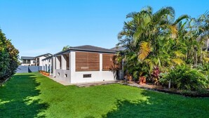 A modern residential area with houses featuring contemporary architecture, well-maintained lawns, and tropical plants. - Beachside living takes a smart & stylish turn with this well appointed apartment (Lennox Head)