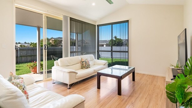 A spacious living room with a white sofa, a glass coffee table, and a ceiling fan. - Beachside living takes a smart & stylish turn with this well appointed apartment (Lennox Head)