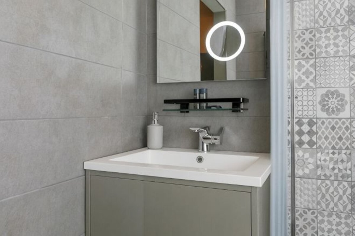 A bathroom with a white sink, a mirror, and a towel dispenser.