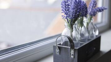 A window with a metal tray holding three glass vases with purple flowers.