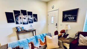 A living room with a sofa, a coffee table, and a TV. There are four framed pictures on the wall.