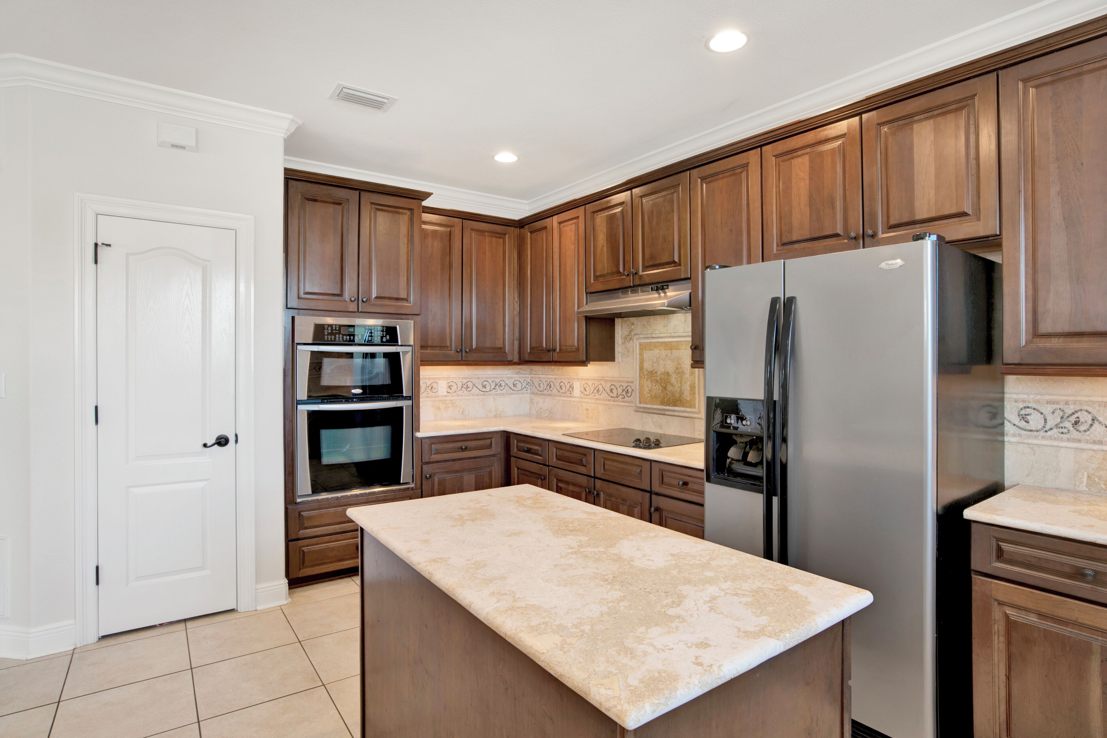 A kitchen with wooden cabinets, a stainless steel refrigerator, an oven, and a countertop.