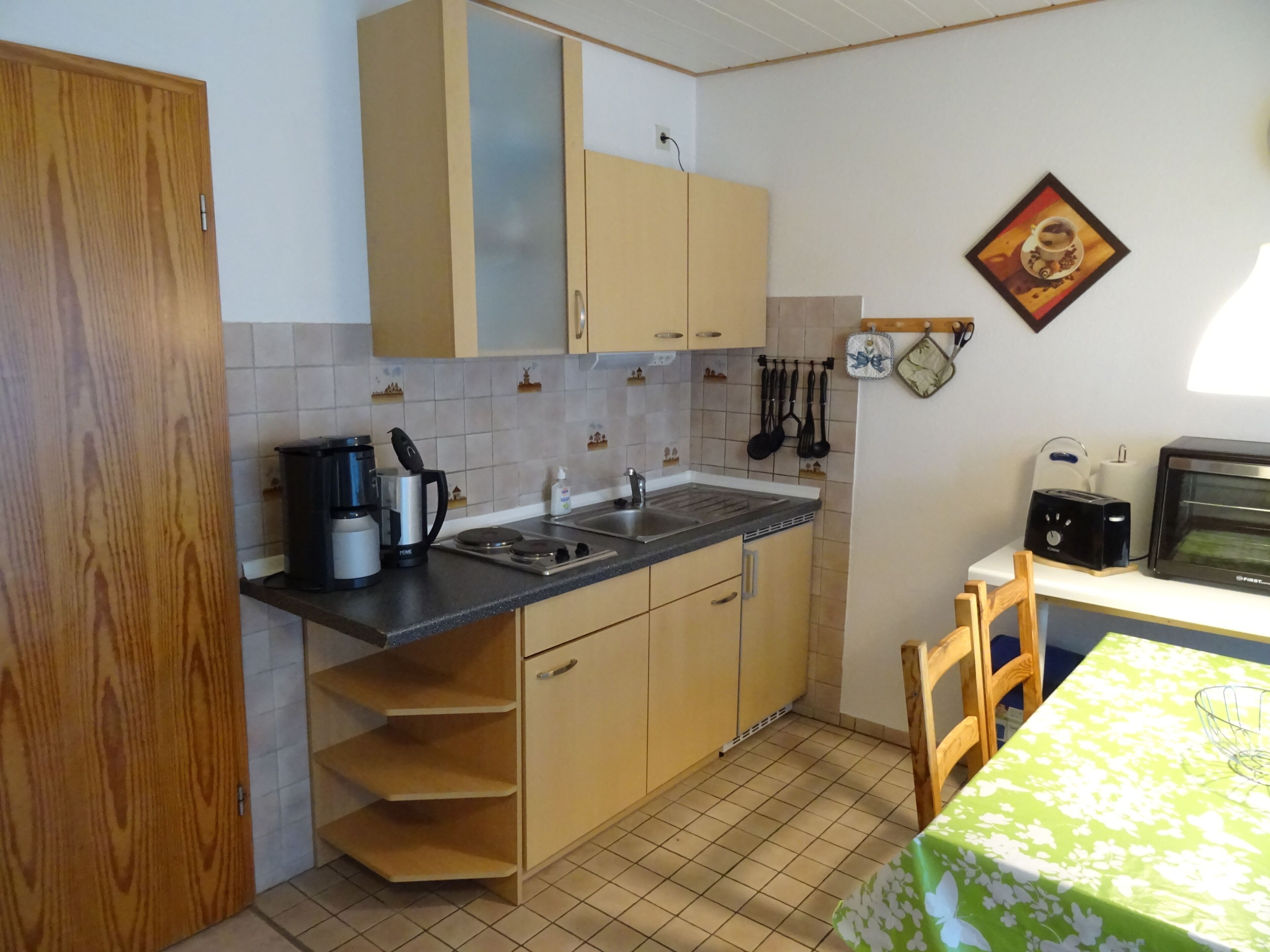 A compact kitchen with wooden cabinets, a coffee maker, a toaster, and a microwave.