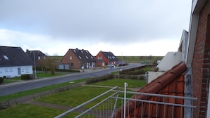 Een woonstraat met huizen, een heldere lucht en een metalen hek in de voorgrond.
