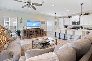 Relax in a spacious living area with a sectional sofa and coffee table, complemented by an entertainment center. Enjoy a well-equipped kitchen with a central island and gas range.