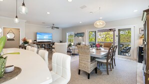 A spacious living room with a large TV, comfortable seating, and a dining area with a table and chairs.