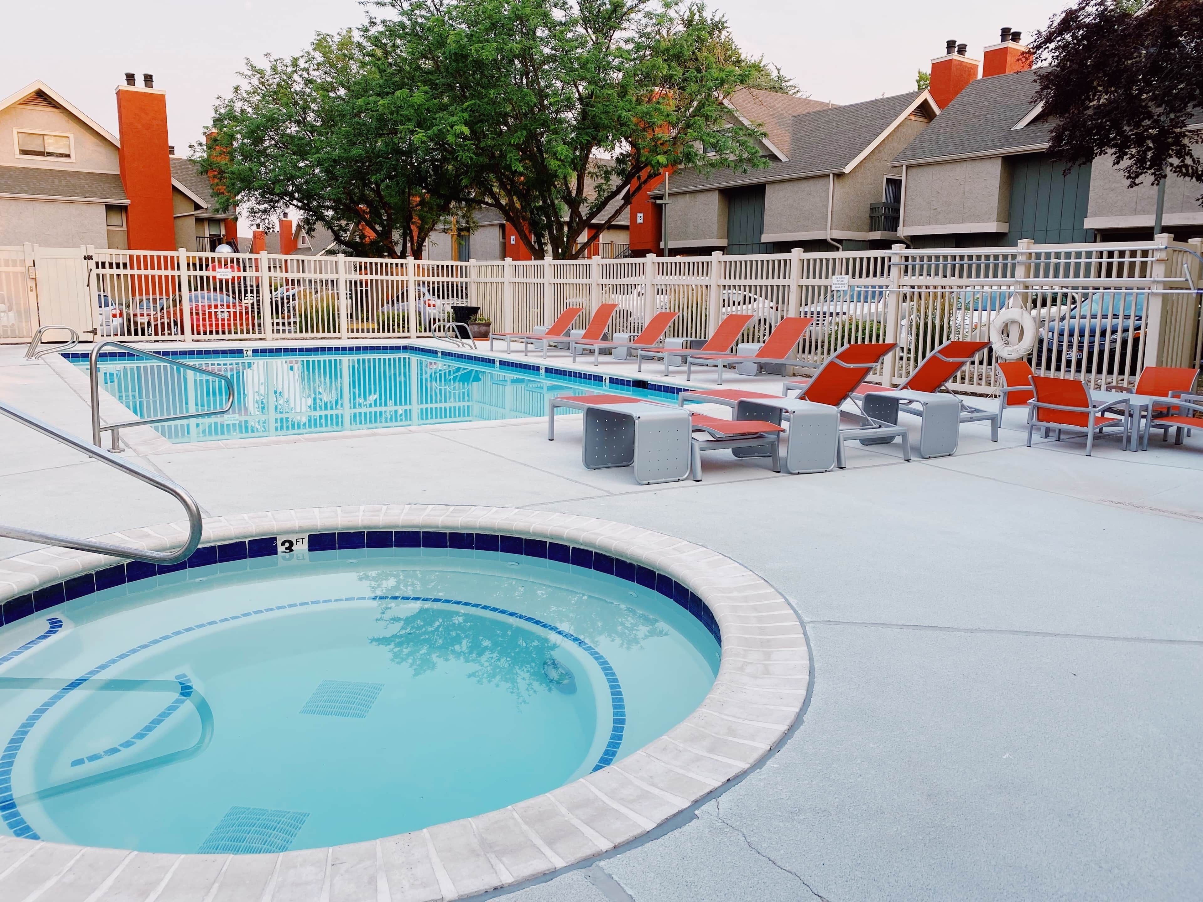 A swimming pool with lounge chairs and a fenced area.