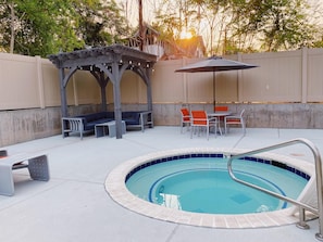 Une piscine dotée d’un espace détente couvert et d’une table avec des chaises.