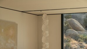 A modern living room with a sofa, a coffee table, and a view of a rocky landscape through a large window.