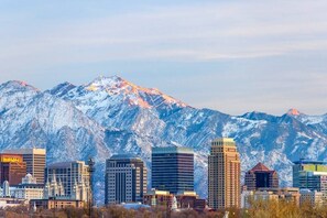A cityscape with modern buildings and a snow-covered mountain in the background. - Two Bedroom Loft, King Beds, Down Town Convenience (Salt Lake City)