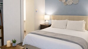 A neatly arranged bedroom with a bed, bedside table, lamp, and a wall decoration. - Down Town, Award Winning KING Bed, Self Check-In (Salt Lake City)