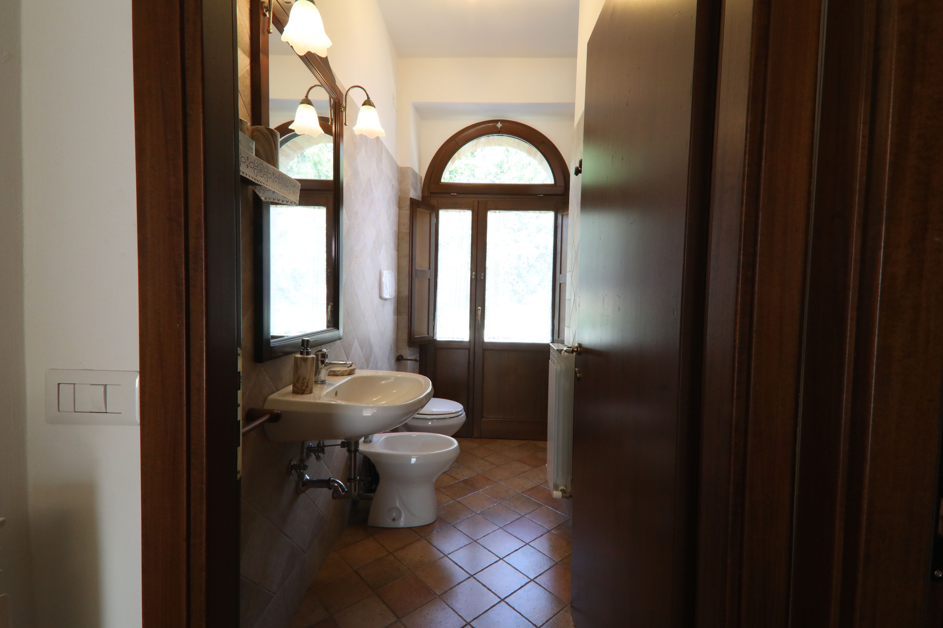 A bathroom with a sink, mirror, and two toilets.