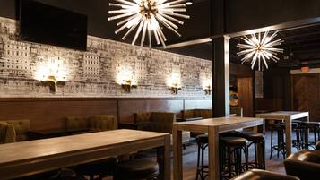 L’intérieur du restaurant est aménagé avec des tables hautes, des banquettes et des tabourets de bar. On y trouve des luminaires fixés aux murs et une grande fresque représentant un paysage urbain.