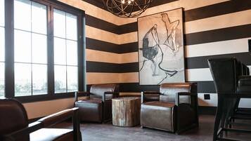 A modern lounge with striped walls, leather seating, and a large abstract painting.