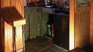 A compact kitchen with wooden cabinets, a stove, and a refrigerator. - Micro house cabin located near Silver Mines Recreation Area. (Fredericktown)