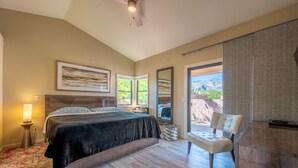 Une chambre à coucher avec un lit, des tables de chevet, une chaise et une vue sur l’extérieur.