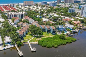 An aerial view of a coastal residential area with modern buildings, a marina, and a large green park.