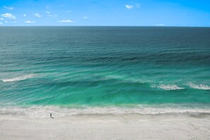 A beach with clear turquoise waters and a person walking along the shore. - Bay Oaks C Ground Floor (Siesta Key)