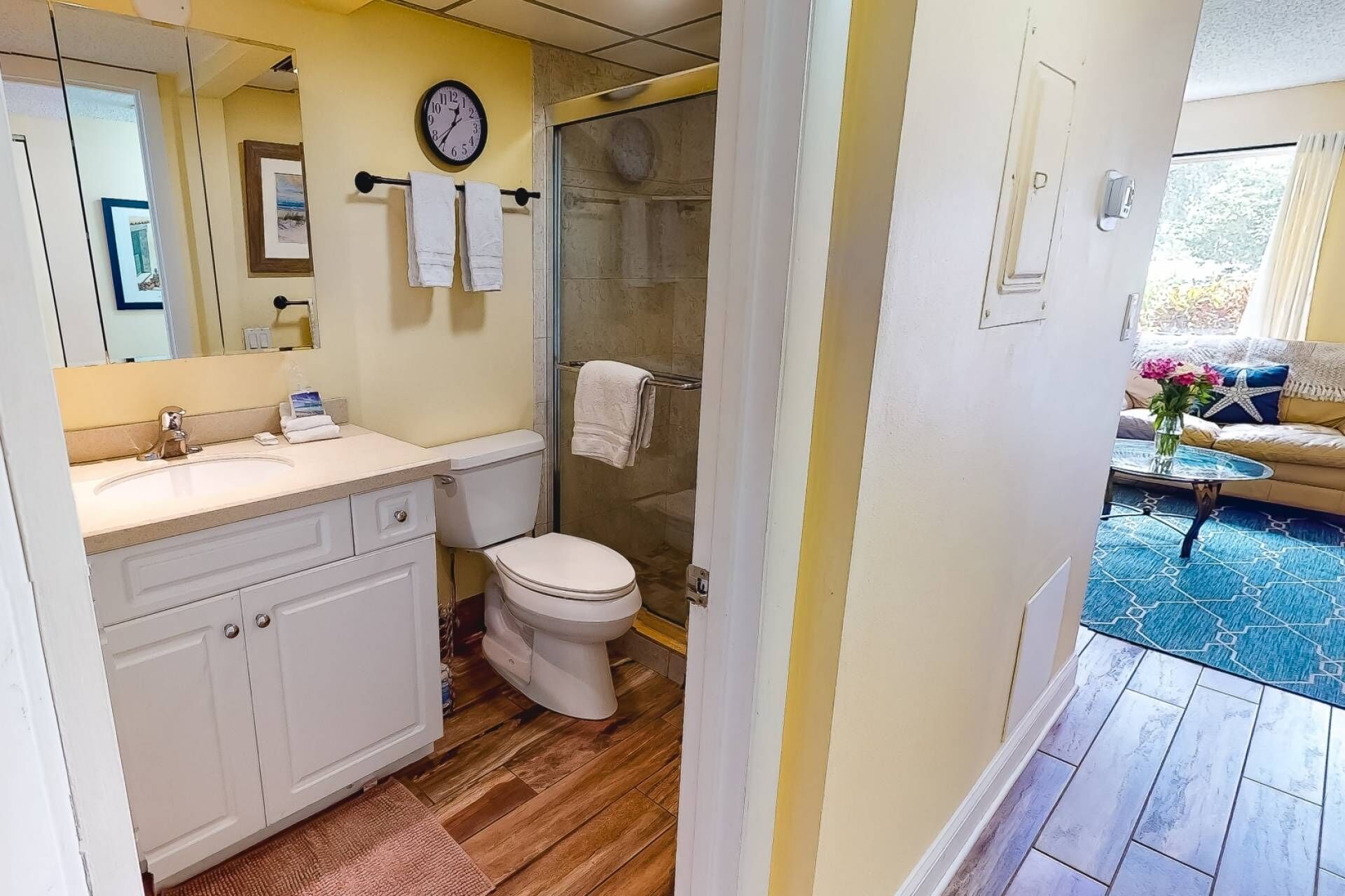 A bathroom with a toilet, sink, and a clock on the wall.