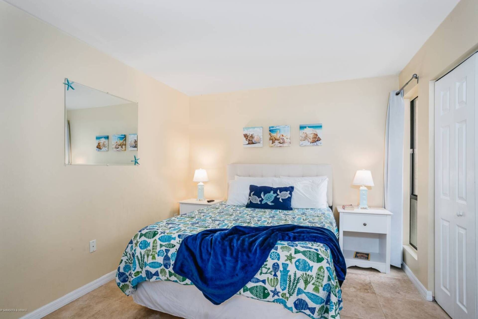 A bedroom with a bed, two bedside tables, a nightstand, a mirror, and a door.