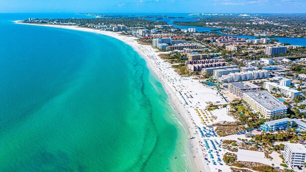 An aerial view of a coastal city with a long sandy beach, numerous hotels, and clear blue waters. - Bay Oaks, 4th Floor Corner - Elevator (Siesta Key)