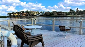 A deck with a table and two chairs overlooking a body of water, with buildings in the background. - Bay Oaks, 4th Floor Corner - Elevator (Siesta Key)