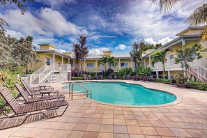 Relax by the resort's central pool, surrounded by lounge chairs and a table.