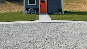 A two-story house with a red door, a small porch, and a gravel driveway. - City Loft  (Trenton)