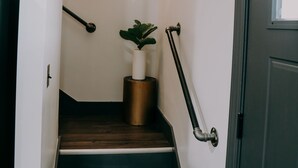A staircase with wooden steps, a potted plant, and a wall-mounted decorative item. - City Loft  (Trenton)