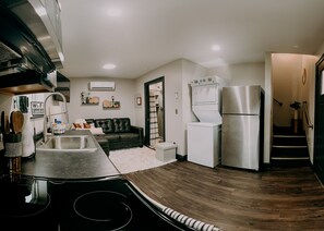 A compact kitchen with a built-in oven, a refrigerator, and a washing machine. - The City Loft (Trenton)