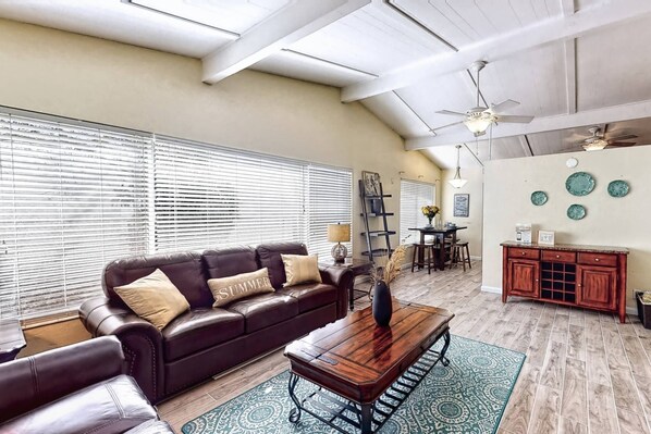 A living room with a leather sofa, wooden coffee table, and a dining area with a red cabinet.