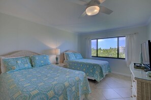 A hotel room with two beds, a ceiling fan, a window with a view, and a TV on a table. - Siesta Dunes on Siesta Key (Siesta Key)