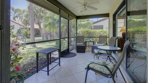 A covered outdoor area with a ceiling fan, a table, and chairs.