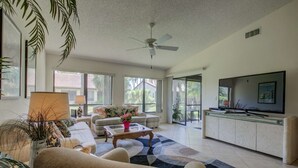 A spacious living room with a sofa, coffee table, and a television.