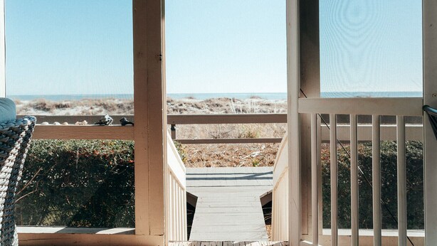 Eine Holzterrasse mit Blick auf Strand und Meer.