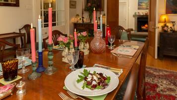 Una mesa de comedor con velas, un florero y un plato de ensalada.