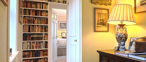 A hallway with a bookshelf, a lamp, and a dresser.