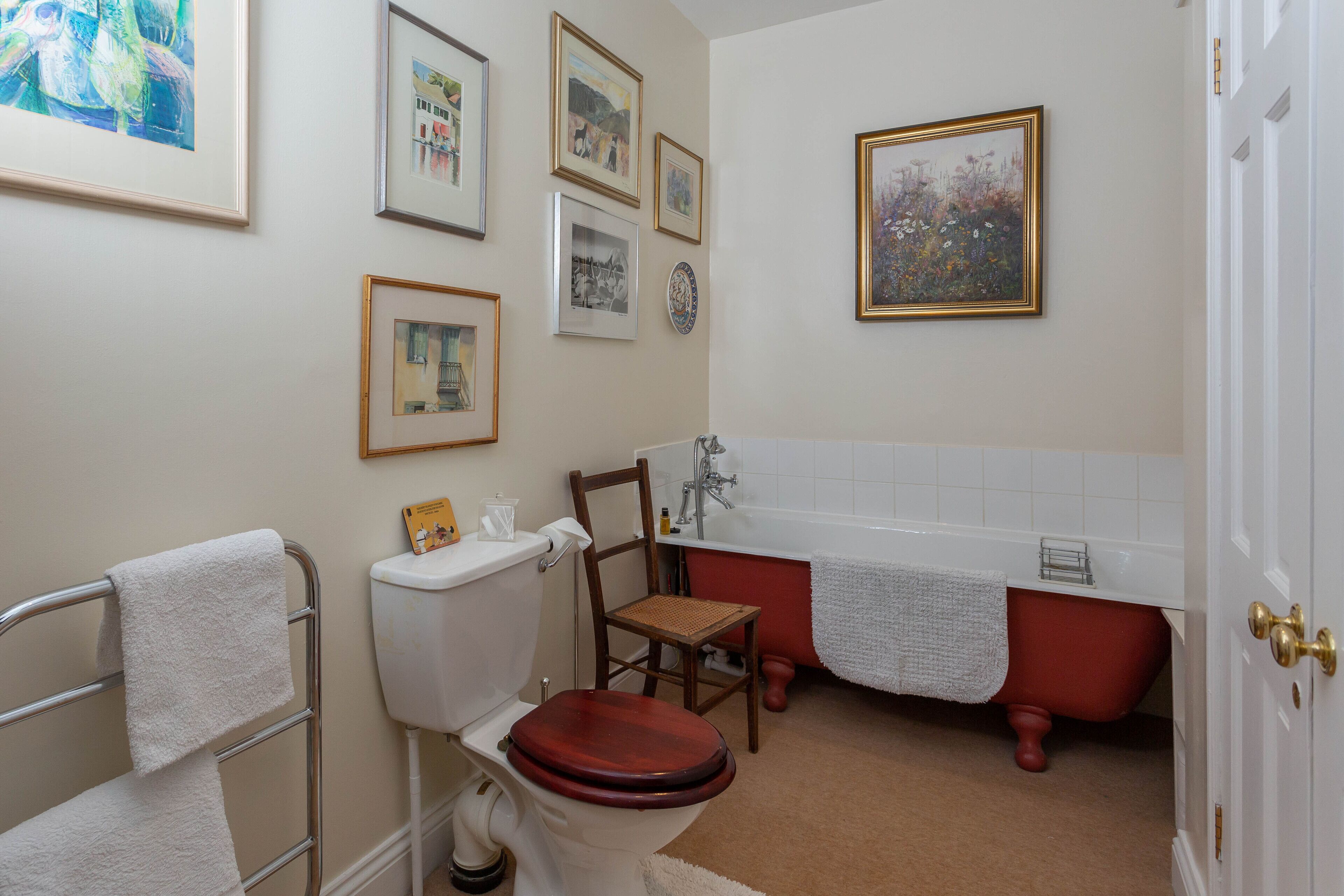 Une salle de bain comprenant des toilettes, une chaise, une baignoire et un lavabo.