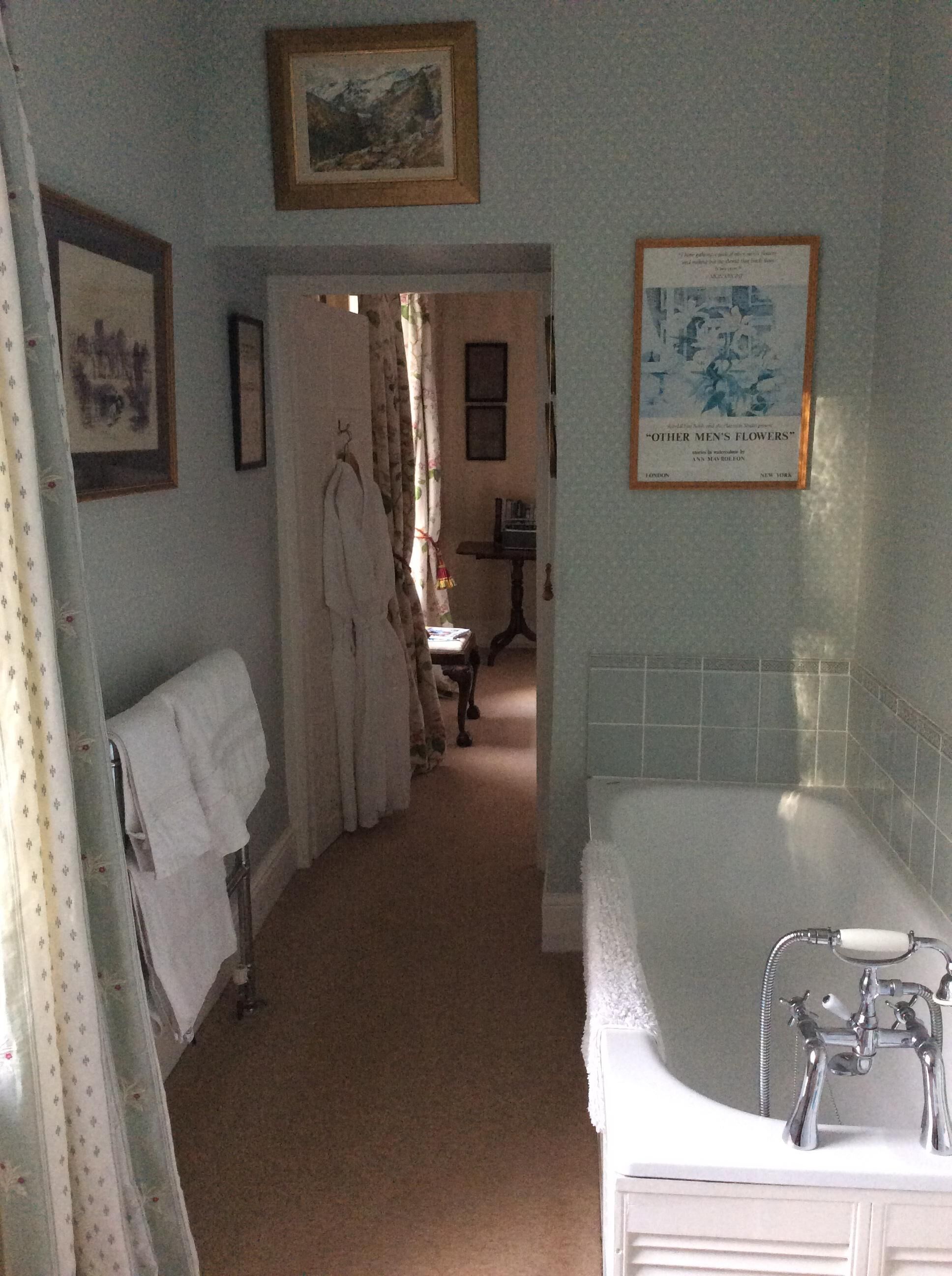 A bathroom with a bathtub, a towel rack, and a framed picture on the wall.