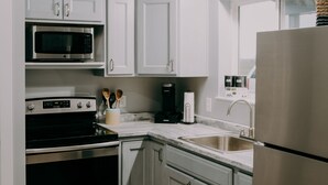 A modern kitchen with white cabinets, stainless steel appliances, and a herringbone-patterned rug.