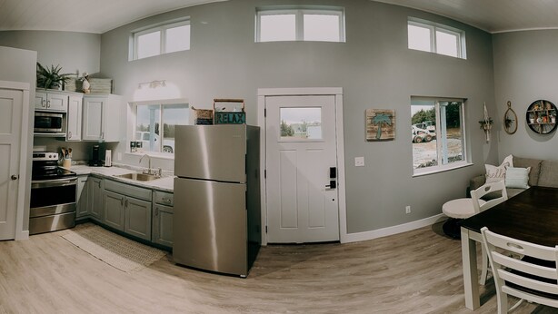 A modern kitchen with a stainless steel refrigerator, white cabinets, and a large window.